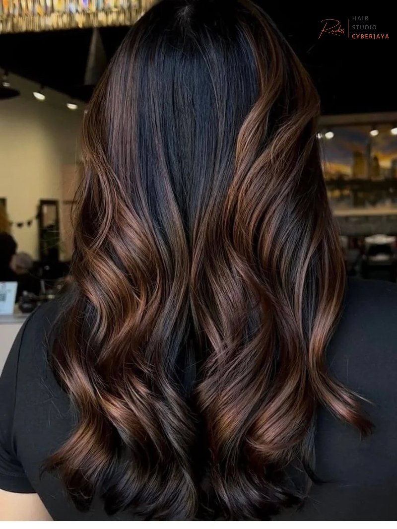 Brunette & Dimensional Color A woman with beautiful warm brunette hair color, showcasing healthy, shiny strands and natural waves.