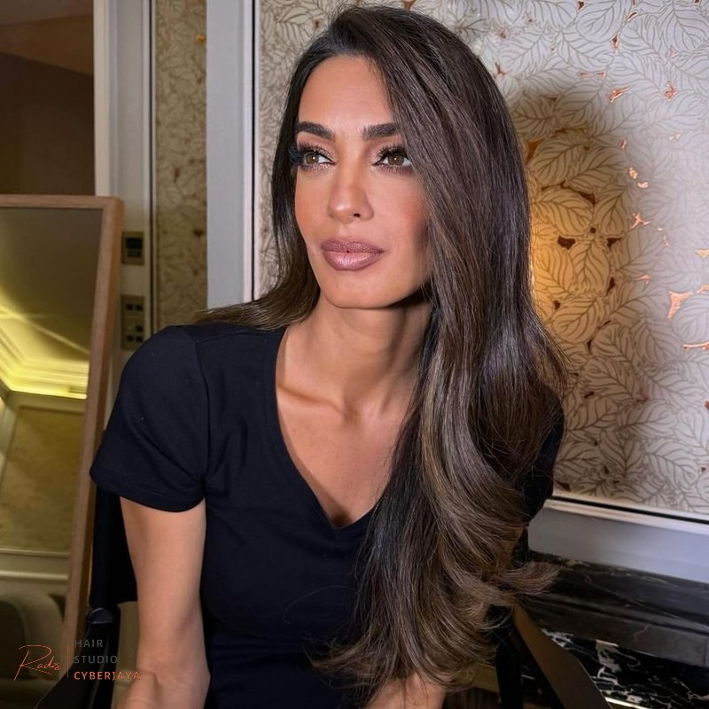 Dark Hair Colors You'll Want to Dye Your Hair ASAP A woman with long, glossy dark hair showcasing subtle ash brown highlights, providing a cool and sophisticated look.