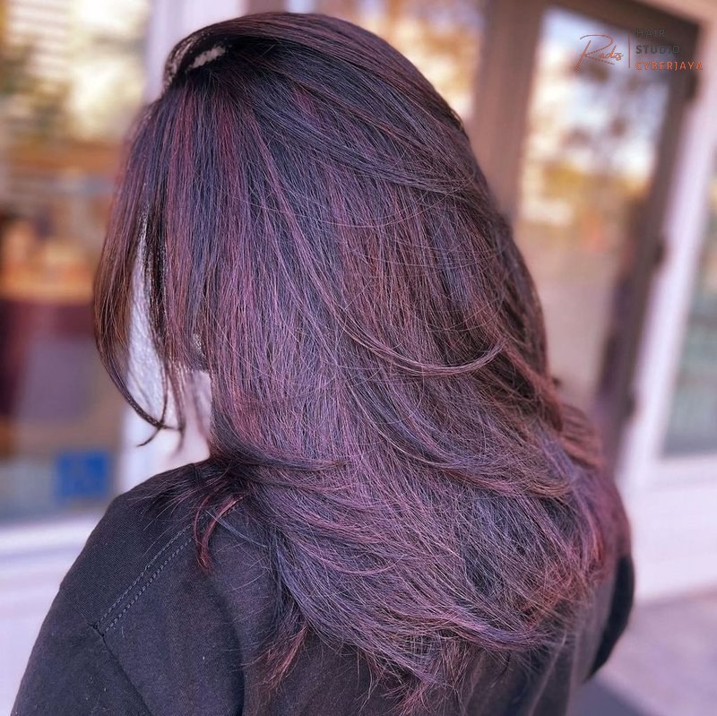 Dark Hair Colors You'll Want to Dye Your Hair ASAP A woman with rich dark brown hair featuring subtle caramel balayage highlights, providing natural dimension.